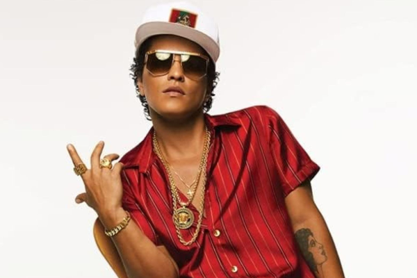 Bruno Mars com óculos escuros e boné fazendo gesto com a mão