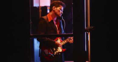 Bruno Mars com uma guitarra dentro de uma cabine telefônica