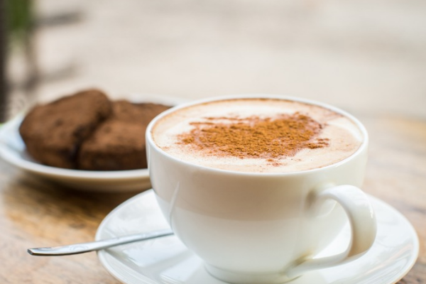 Xícara de capuccino com bolo de chocolate ao lado 